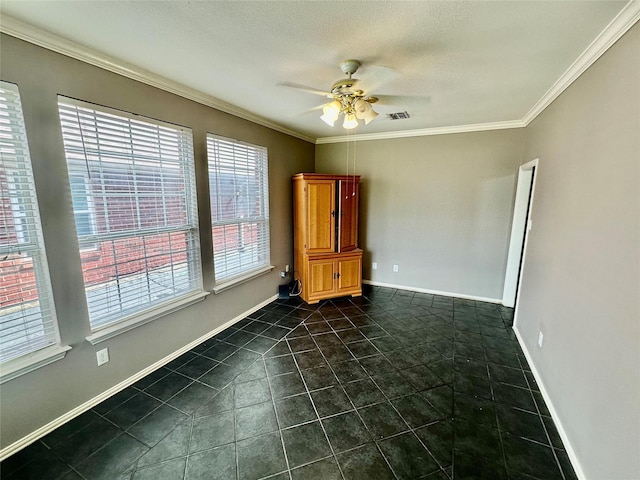 spare room with a ceiling fan, crown molding, dark tile patterned flooring, and baseboards