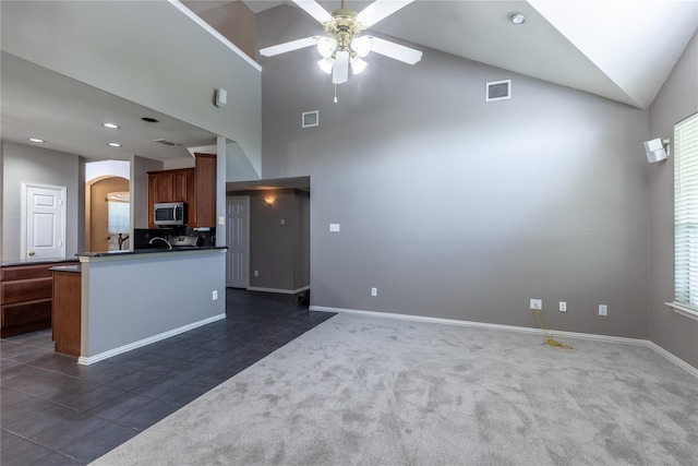 kitchen with kitchen peninsula, dark tile patterned floors, vaulted ceiling, and ceiling fan