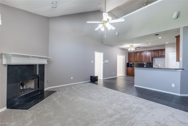 unfurnished living room with high vaulted ceiling, ceiling fan, dark tile patterned floors, beamed ceiling, and a tiled fireplace