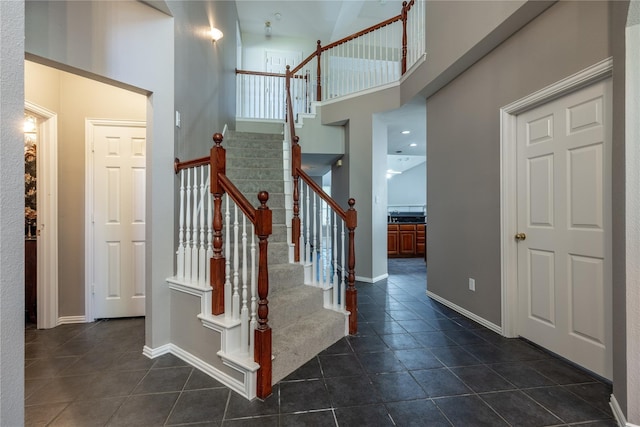 staircase with tile patterned flooring and a high ceiling