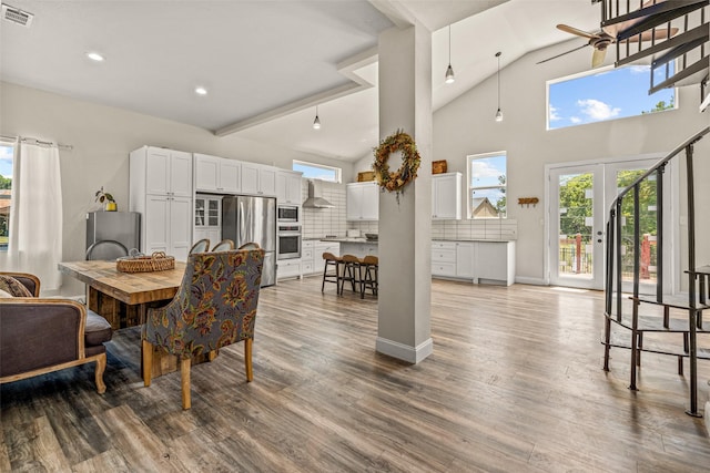 dining area featuring ceiling fan, french doors, high vaulted ceiling, and wood-type flooring