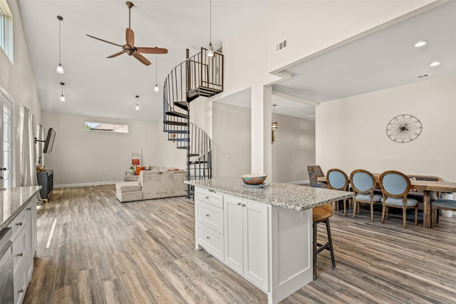 kitchen with white cabinets, a breakfast bar, light stone countertops, and ceiling fan