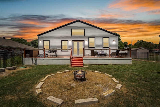 back house at dusk featuring a lawn, a patio area, french doors, and a fire pit