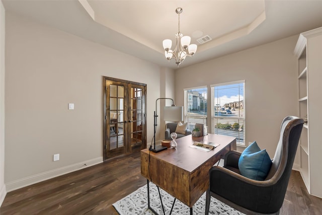 home office with a notable chandelier, dark hardwood / wood-style flooring, french doors, and a raised ceiling