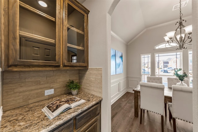 dining room with ornamental molding, dark wood-type flooring, an inviting chandelier, and lofted ceiling