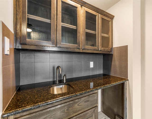 kitchen with sink, dark stone countertops, tasteful backsplash, and dark brown cabinetry