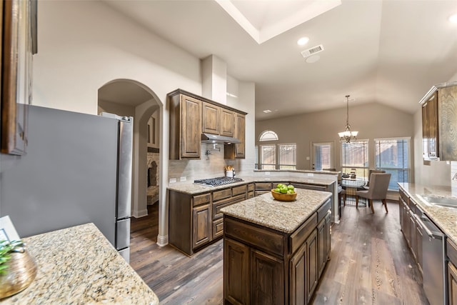 kitchen with dark hardwood / wood-style floors, a kitchen island, an inviting chandelier, backsplash, and appliances with stainless steel finishes