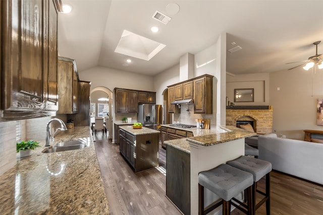 kitchen featuring light stone counters, stainless steel appliances, a kitchen island, backsplash, and sink