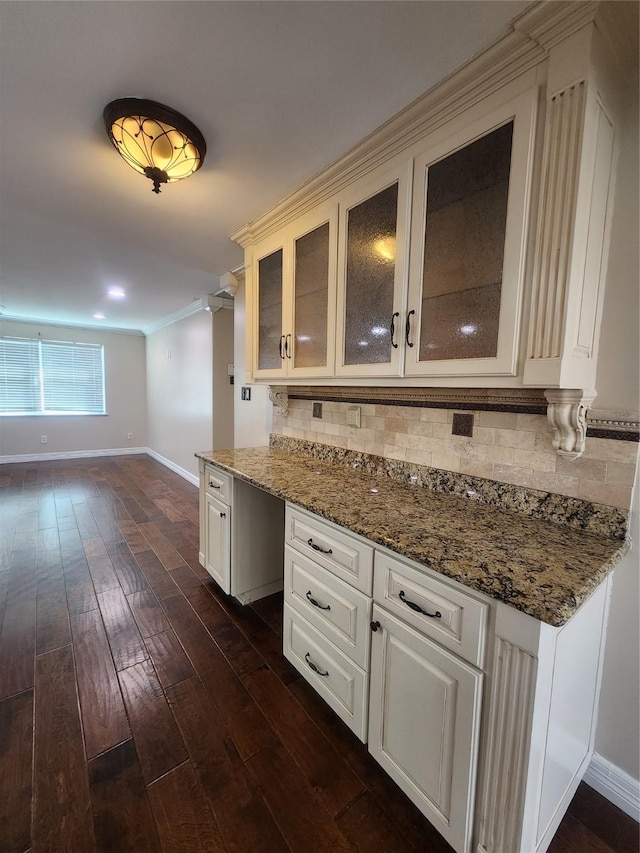 kitchen with dark wood-type flooring, dark stone countertops, backsplash, and white cabinetry