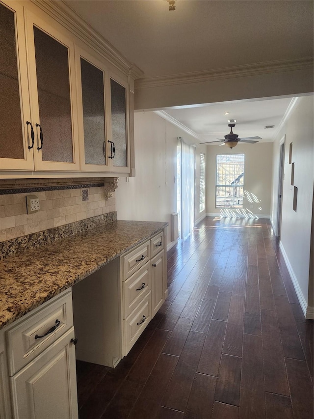 kitchen featuring built in desk, decorative backsplash, ornamental molding, and ceiling fan