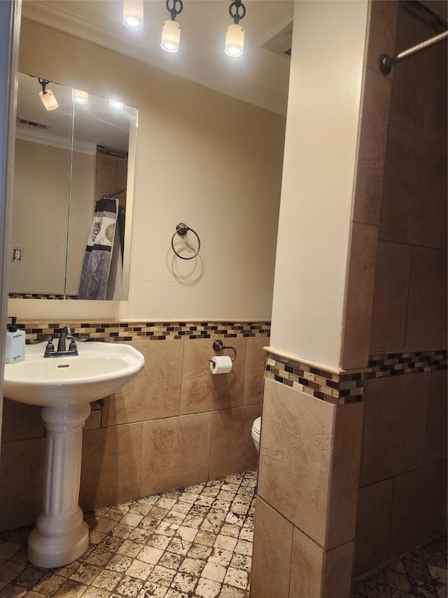 bathroom featuring tile walls, toilet, and crown molding