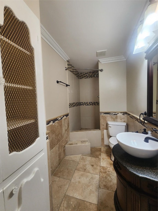 full bathroom featuring tiled shower / bath, tile walls, toilet, vanity, and crown molding