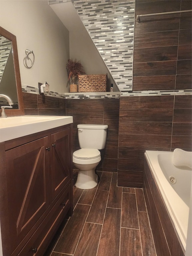 bathroom with toilet, vanity, tile walls, and tiled bath