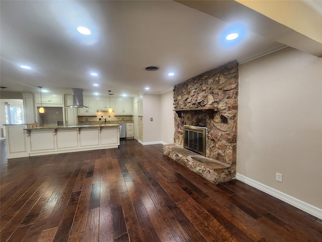 unfurnished living room with crown molding, dark hardwood / wood-style flooring, and a stone fireplace