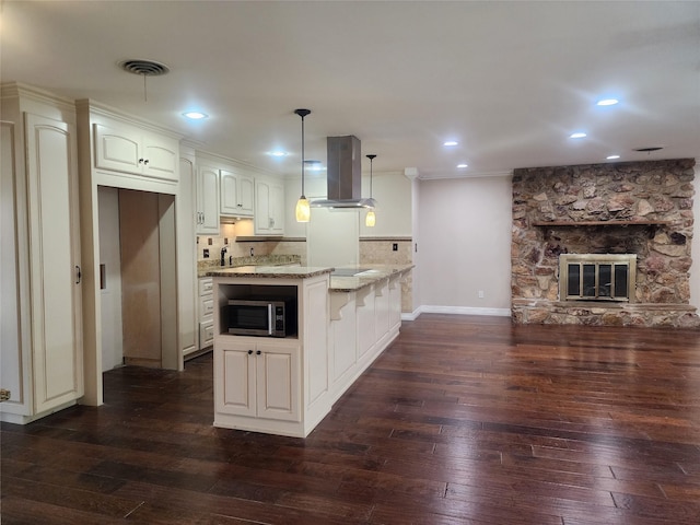 kitchen featuring light stone countertops, a fireplace, island range hood, and dark hardwood / wood-style floors