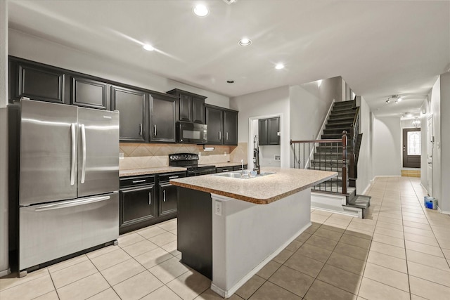 kitchen featuring decorative backsplash, sink, black appliances, a center island with sink, and light tile patterned flooring