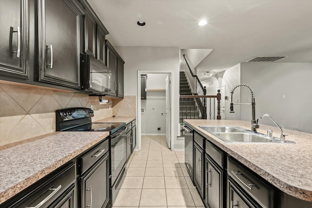 kitchen with a kitchen island with sink, black appliances, sink, decorative backsplash, and light tile patterned flooring