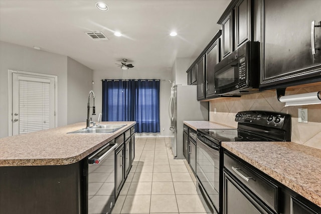 kitchen with sink, tasteful backsplash, an island with sink, light tile patterned flooring, and black appliances