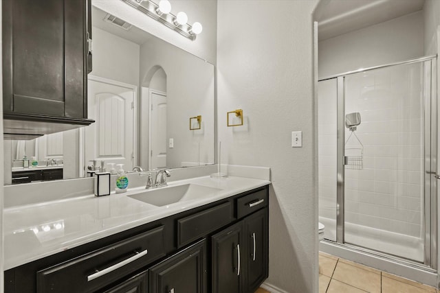 bathroom featuring tile patterned flooring, vanity, toilet, and an enclosed shower