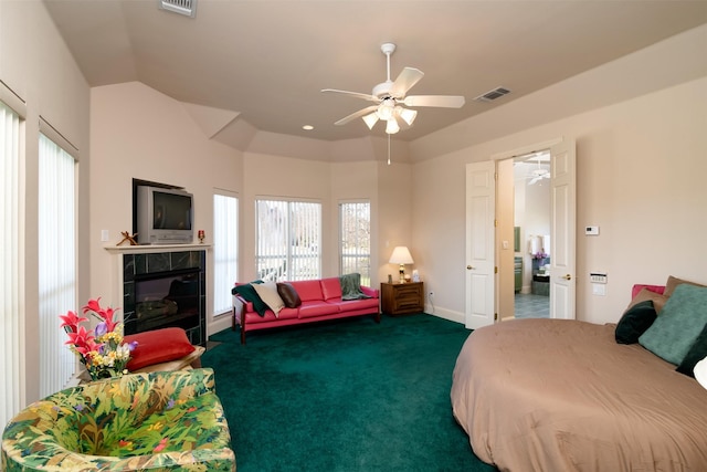 carpeted bedroom featuring a tile fireplace, ceiling fan, and lofted ceiling