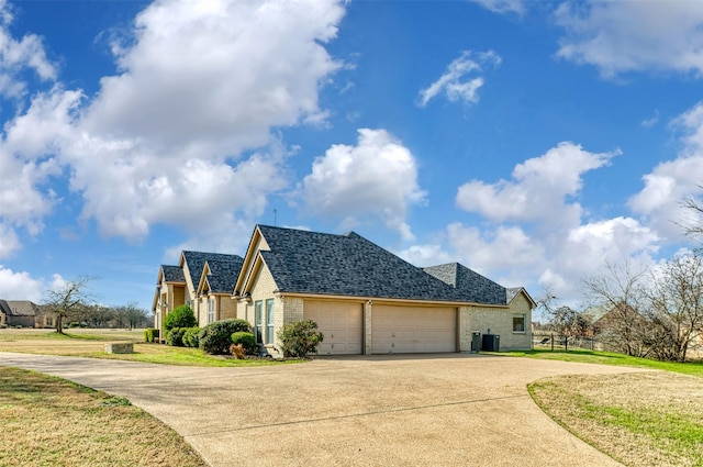 view of side of home with a lawn, central AC unit, and a garage