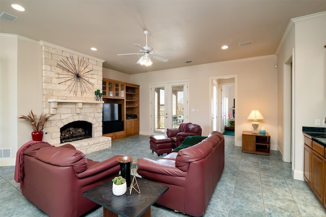 living room with french doors, a stone fireplace, ceiling fan, and crown molding