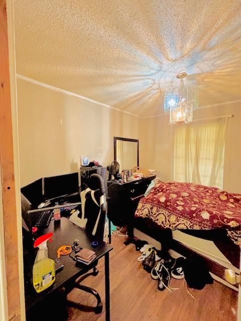 bedroom featuring a chandelier, wood-type flooring, a textured ceiling, and ornamental molding