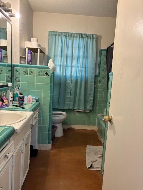 full bathroom with shower / bathtub combination with curtain, vanity, tile walls, and toilet