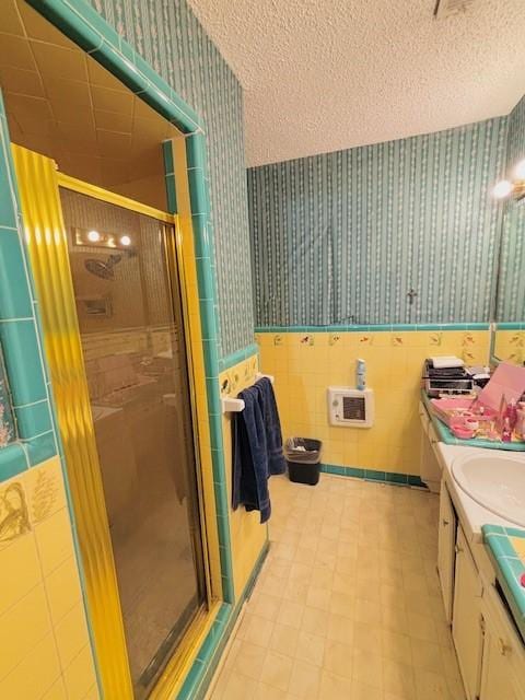 bathroom with heating unit, vanity, a textured ceiling, and walk in shower