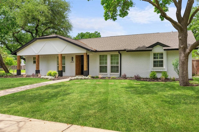 ranch-style house featuring brick siding, a front yard, fence, and roof with shingles