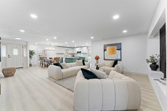 living area with baseboards, light wood finished floors, recessed lighting, and a notable chandelier