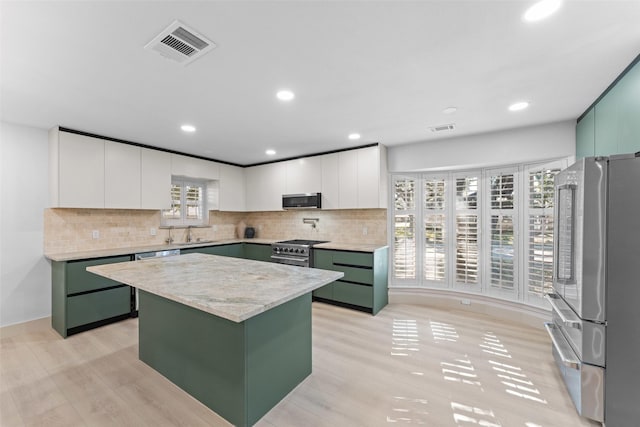 kitchen with visible vents, a sink, green cabinets, and stainless steel appliances