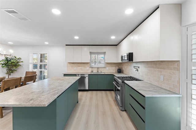 kitchen with white cabinets, green cabinetry, stainless steel appliances, light wood-type flooring, and visible vents