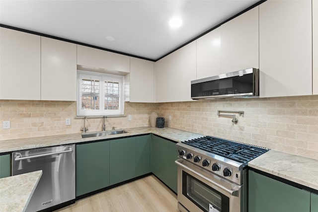kitchen featuring light wood-type flooring, white cabinetry, a sink, appliances with stainless steel finishes, and green cabinets