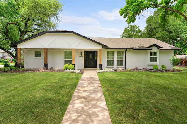 ranch-style house featuring a shingled roof, a front lawn, and brick siding