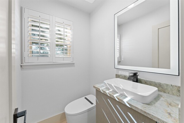 half bath featuring vanity and toilet