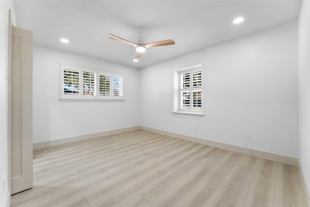 empty room featuring a healthy amount of sunlight, a ceiling fan, recessed lighting, and wood finished floors