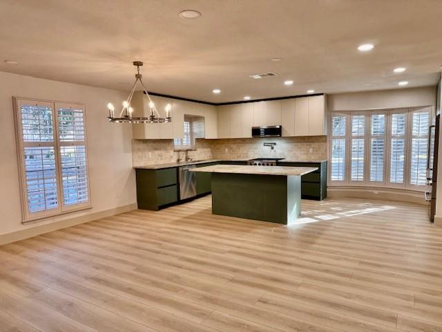 kitchen featuring white cabinets, a center island, decorative light fixtures, and light hardwood / wood-style floors