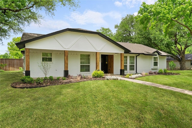 ranch-style home featuring fence, a shingled roof, a front lawn, and brick siding