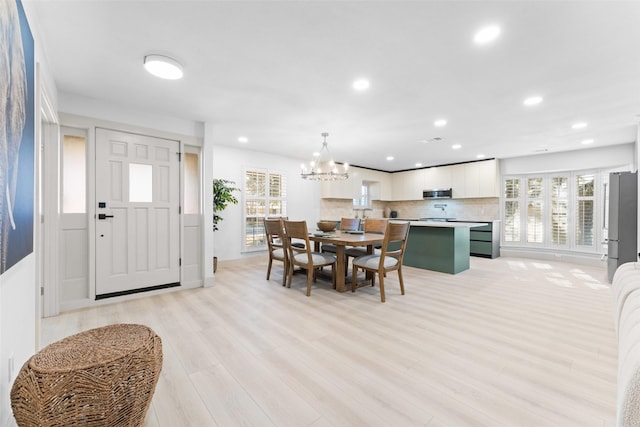 dining space with recessed lighting, a notable chandelier, and light wood finished floors