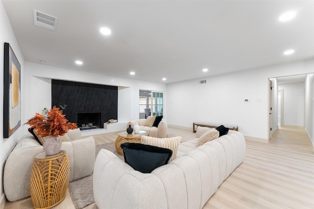 living area with visible vents, recessed lighting, light wood-style flooring, and a premium fireplace