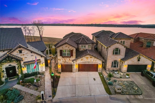 mediterranean / spanish-style home with a garage and a water view