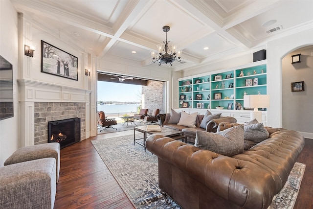 living room with beam ceiling, a water view, coffered ceiling, and a brick fireplace