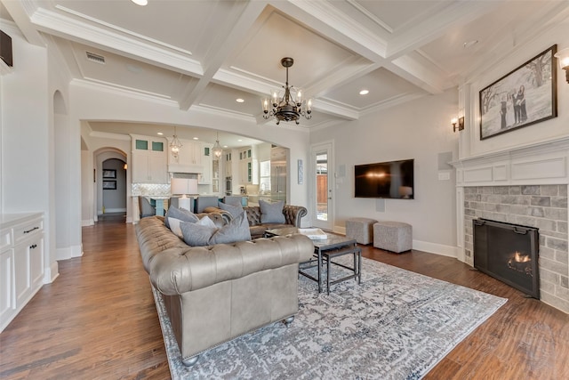 living room with beamed ceiling, ornamental molding, and a fireplace