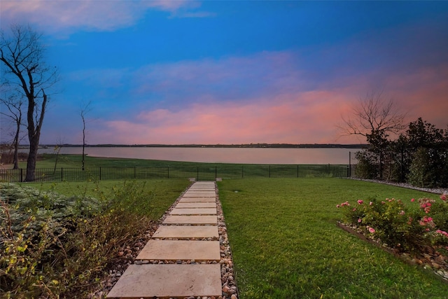 yard at dusk featuring a water view