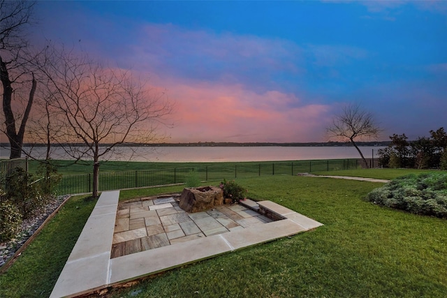 yard at dusk with a water view, an outdoor fire pit, and a patio area