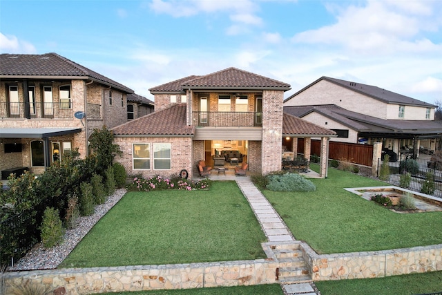 back of property with a lawn, a balcony, and a patio