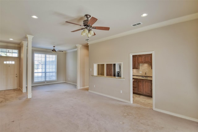 unfurnished living room with ceiling fan, light colored carpet, crown molding, and decorative columns