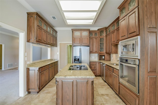 kitchen with crown molding, stainless steel appliances, a kitchen island with sink, and light carpet