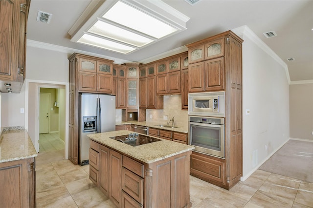 kitchen featuring sink, light stone countertops, ornamental molding, appliances with stainless steel finishes, and a kitchen island